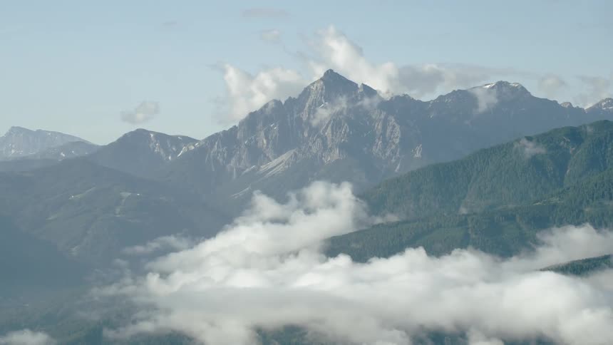White clouds floating over large green mountain range