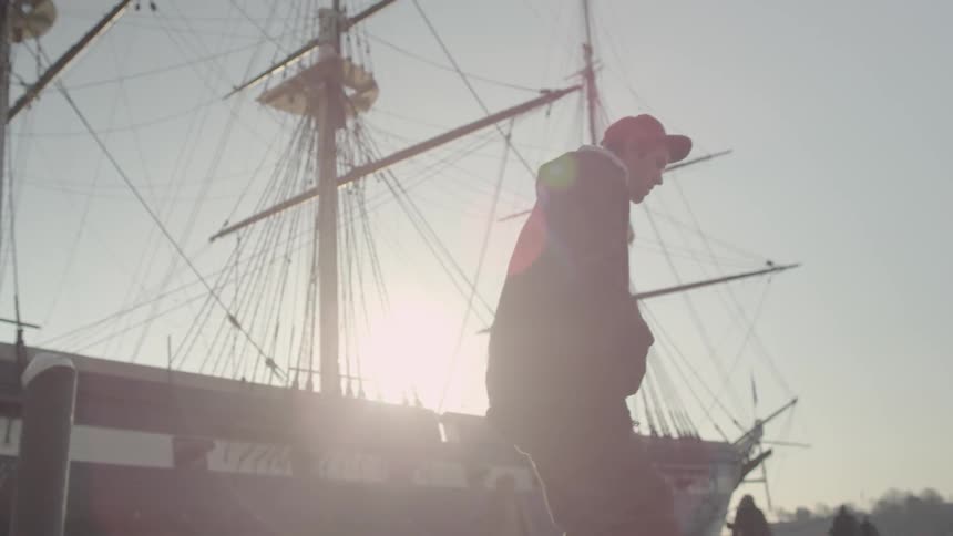 A skateboarder rides next to a docked boat