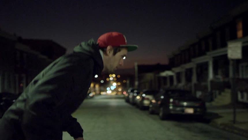 A man is riding a skateboard across a street at night