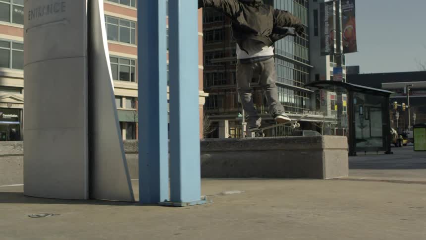 A skateboarder jumps and grinds on a concrete bench
