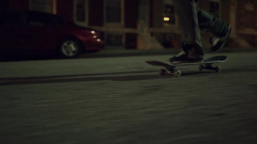 Someone is skateboarding down the street at night