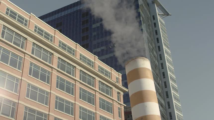 Smoke rises from a smokestack in a city