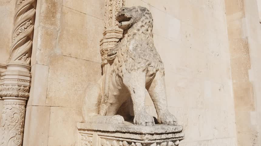 A statue of an animal sits outside a stone building