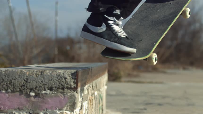 A skateboarder jumps on a concrete barrier