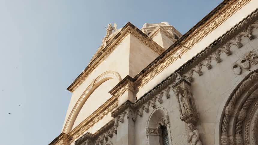 Birds fly around the exterior of an old world church during the day