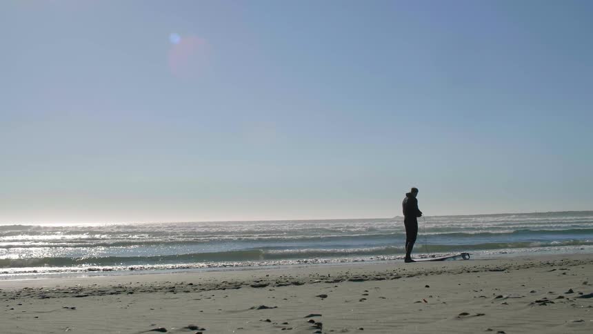 Man stands on beach at ocean's edge
