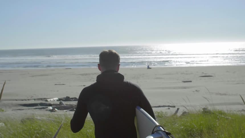 A surfer walks towards a beach