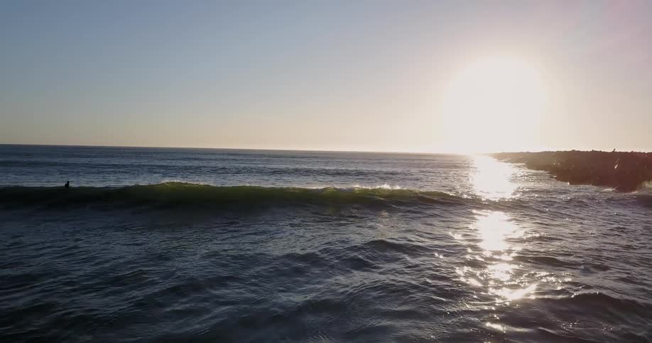 Surfers are paddling out to sea through the waves during the day