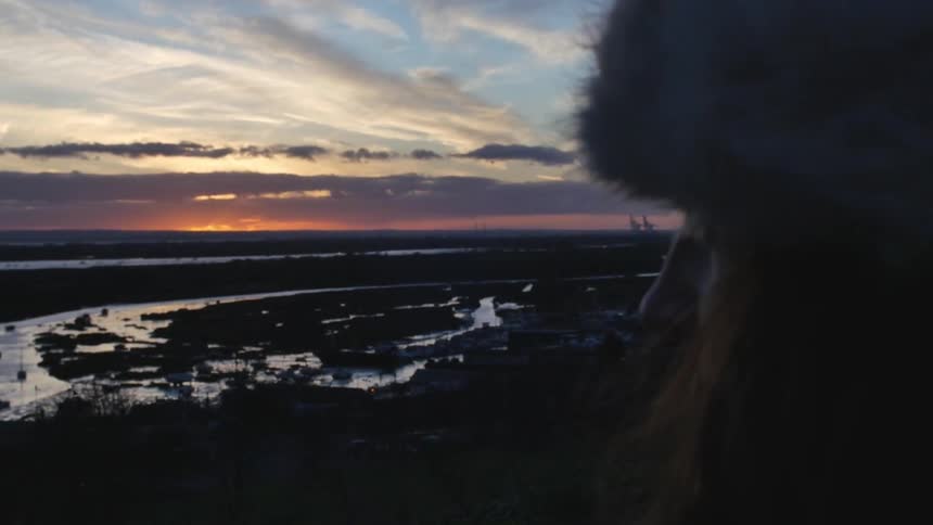 Woman watches as the sun goes down in the distance