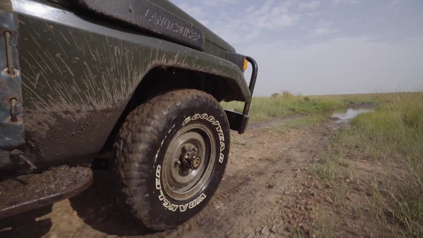 Vehicle travels through a grassy field and through a large puddle