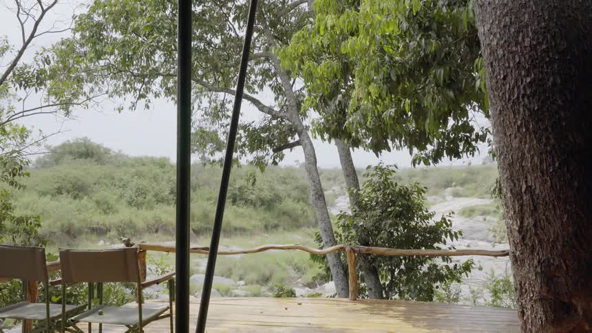 A tent with tables and chairs overlooks a river