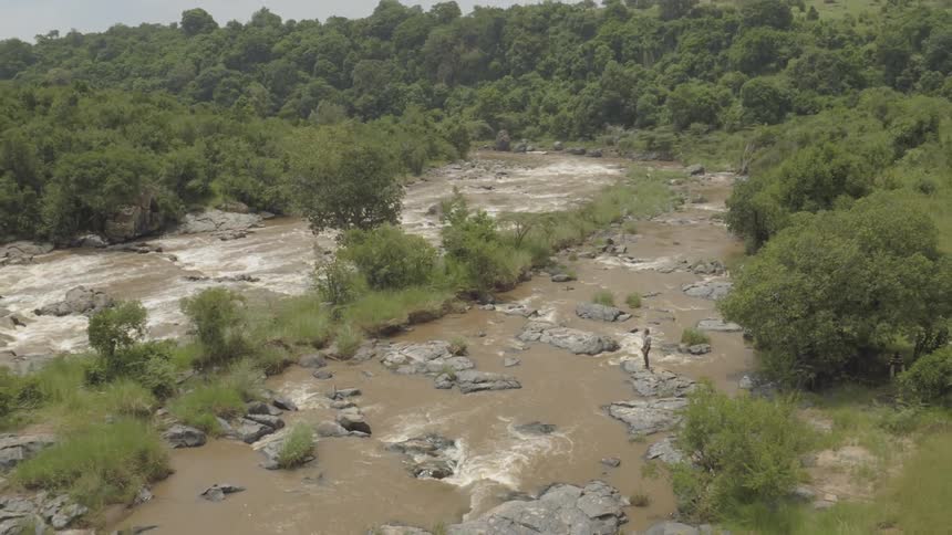 A man stands on the side watching the large stream