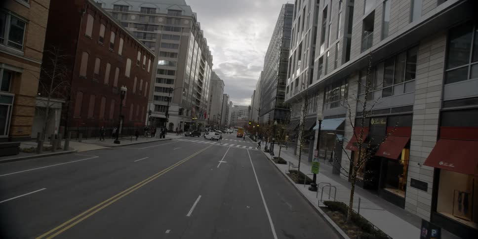 Pedestrians walk across a street in a city on a cloudy morning