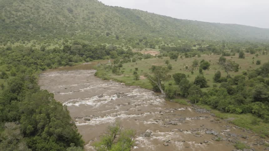 The stream is running through the field by the mountain