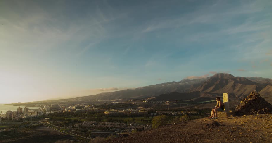 Timelapse of people sitting on a bench on a mountain watching the city below
