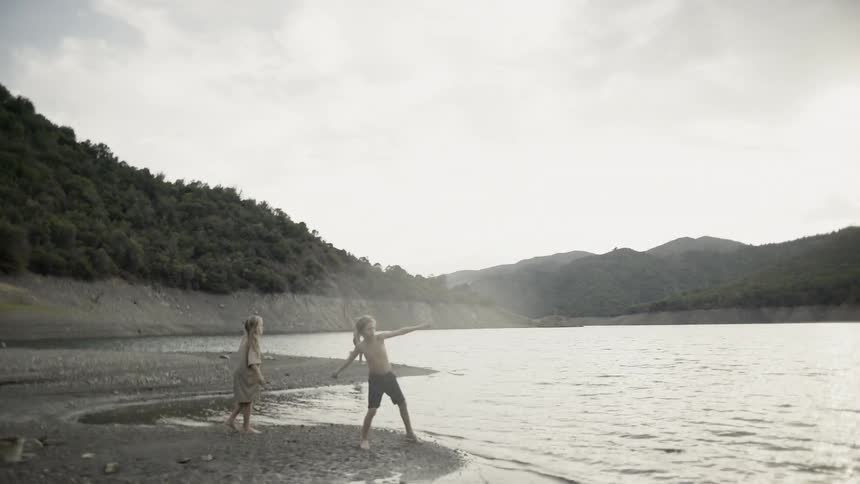 Kids throw rocks into a lake