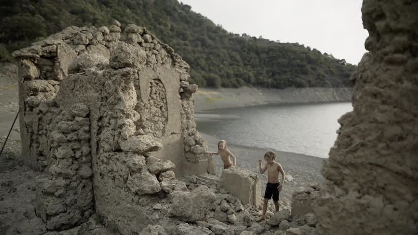 Boys climb on stone ruins on a beach