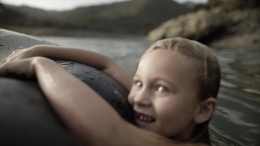 A young child plays with a raft in the water
