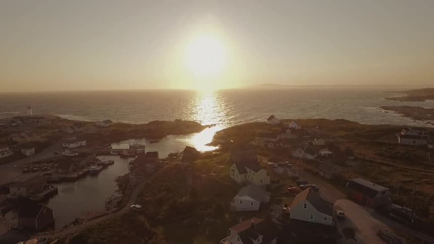 There are many houses along the shore at sunset