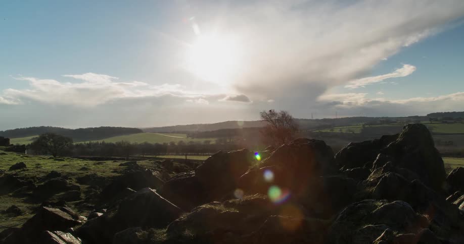 Time lapse from rocks overseeing a large field with clouds above moving