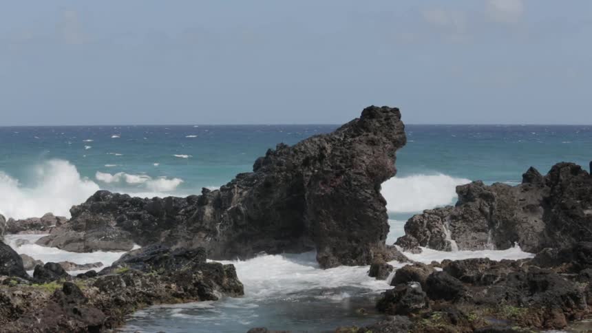 Waves splashing high on some rocks by the shore