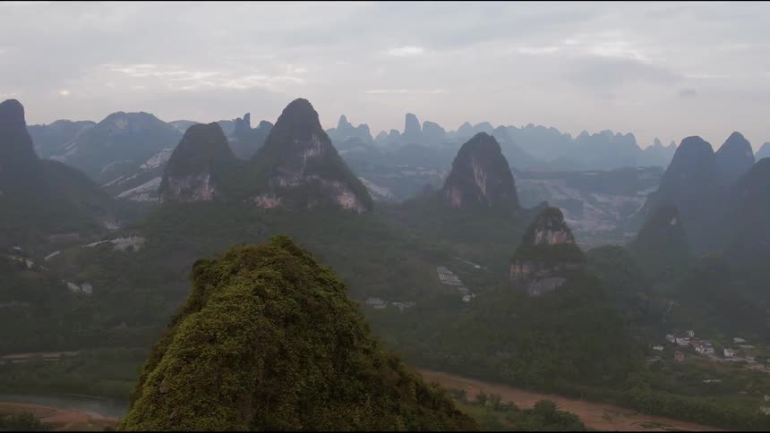 Clouds hang over a village nestled at the base of mountains
