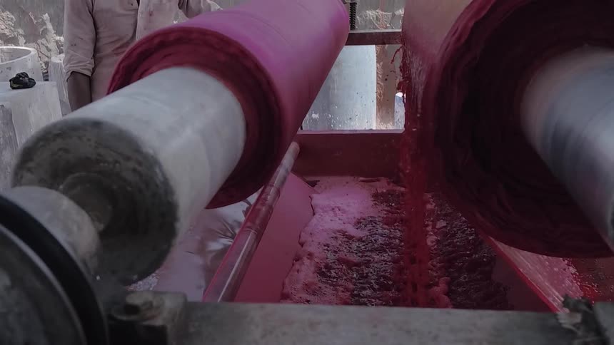 Man stands next to a machine spinning and dripping purple liquid