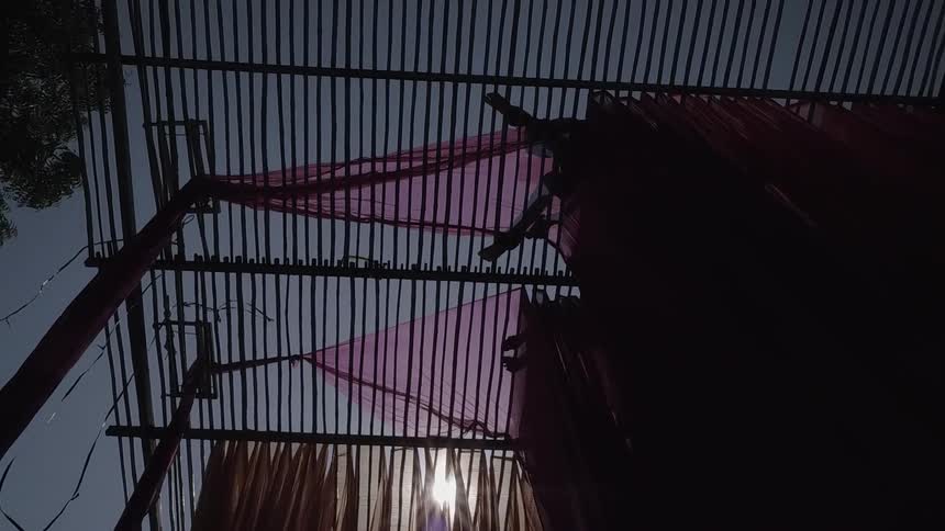 People are smoothing and hanging fabric from rafters during the day