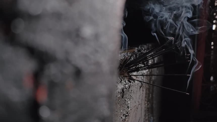 Smoke plumes from incense lodged in a wall