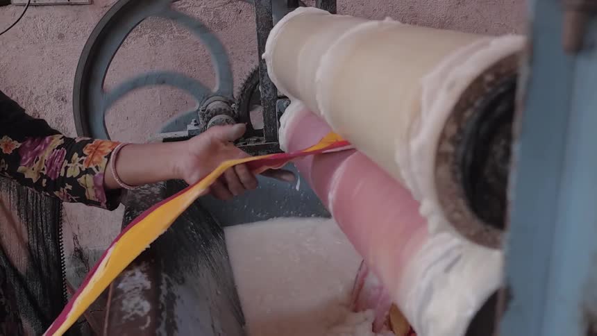 Textiles are fed through a washing machine