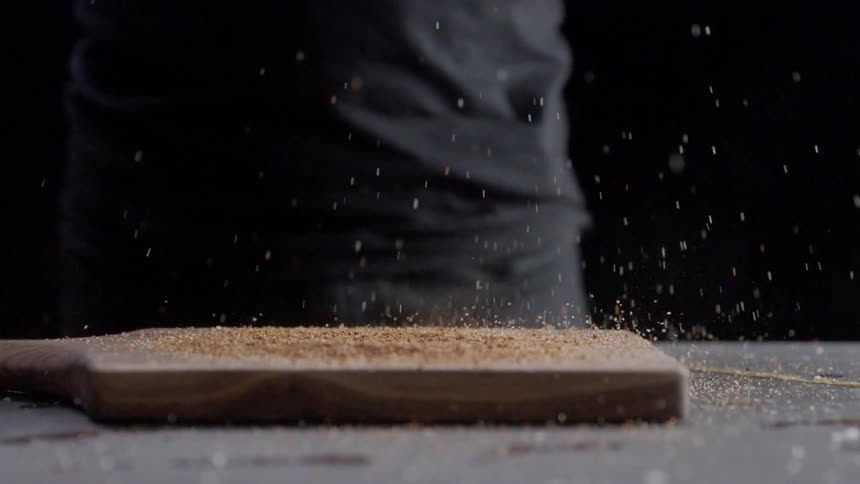 Someone drops a cutting board onto the table and salt flies up