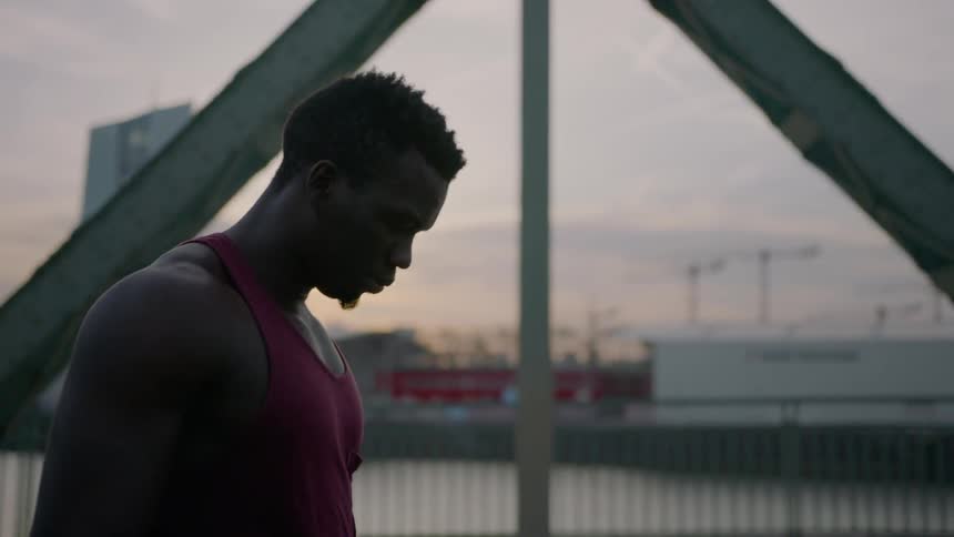 A man in a tank top is walking across a bridge