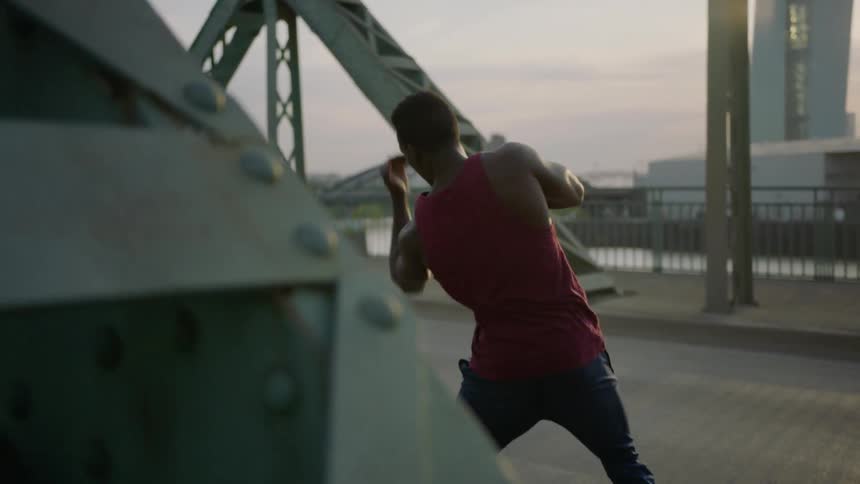 Man practices boxing on a bridge