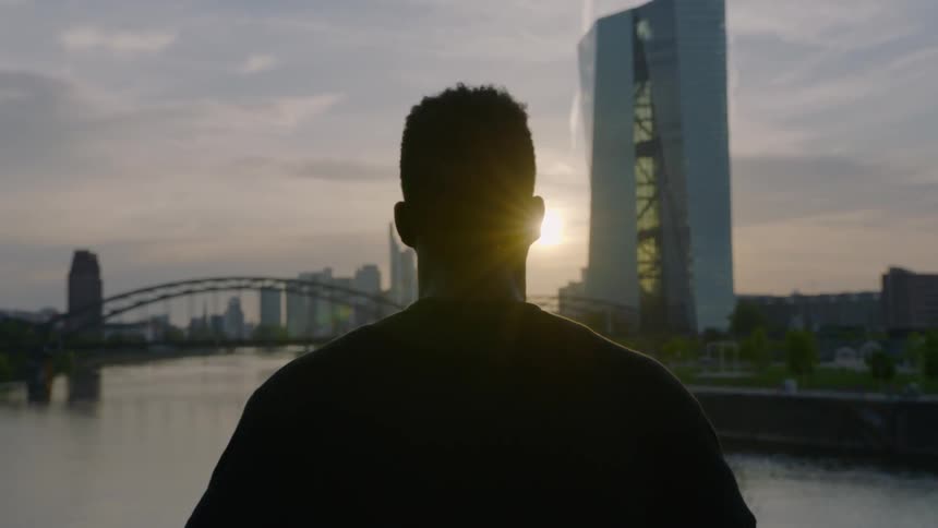 A man is looking out over the river at the city