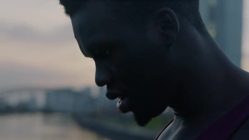 Man breathes heavily outside at sunset