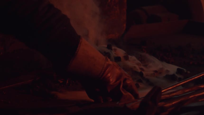 Someone lifting a fireplace poker and dropping it back down next to a pile of smoldering ashes