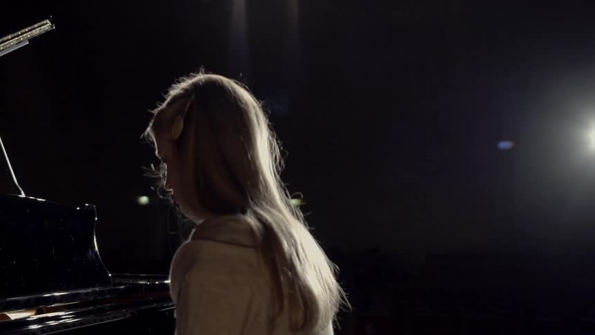A woman is sitting in front of a piano
