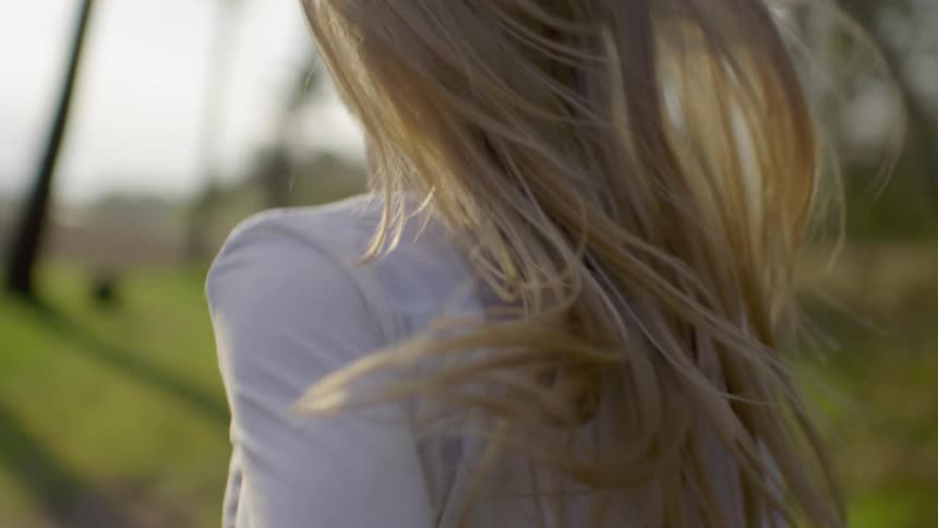 A young woman is running down a dirt path and her hair is bouncing around