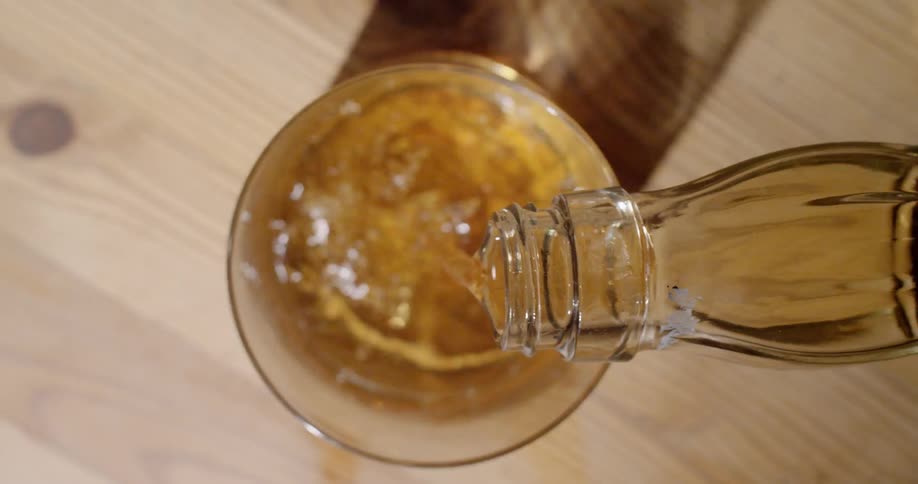 Someone pours liquor into a glass