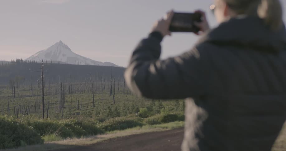 Someone is taking a picture of a large mountain in the distance