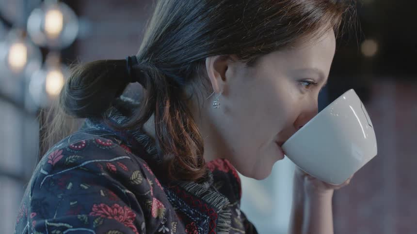 A woman takes a sip of coffee in a cafe