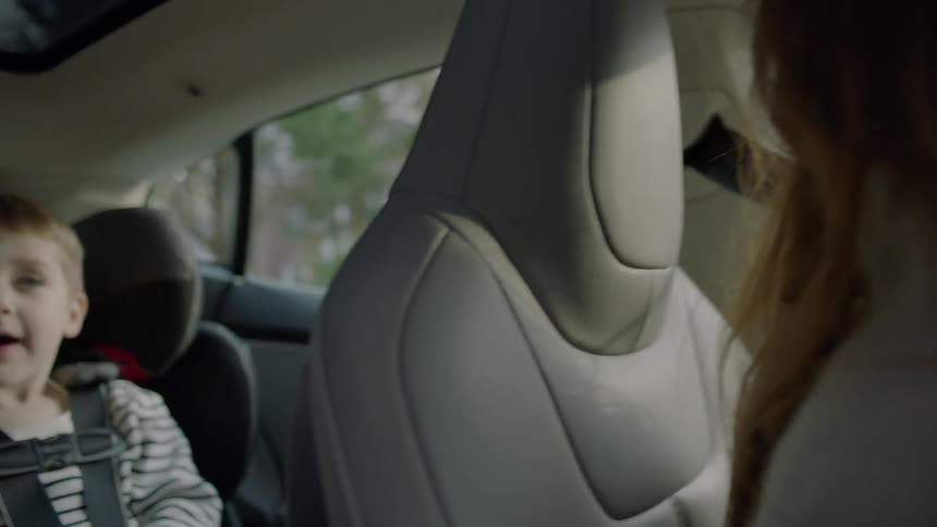 A woman is glancing in her rear view mirror to see a small child in a car seat