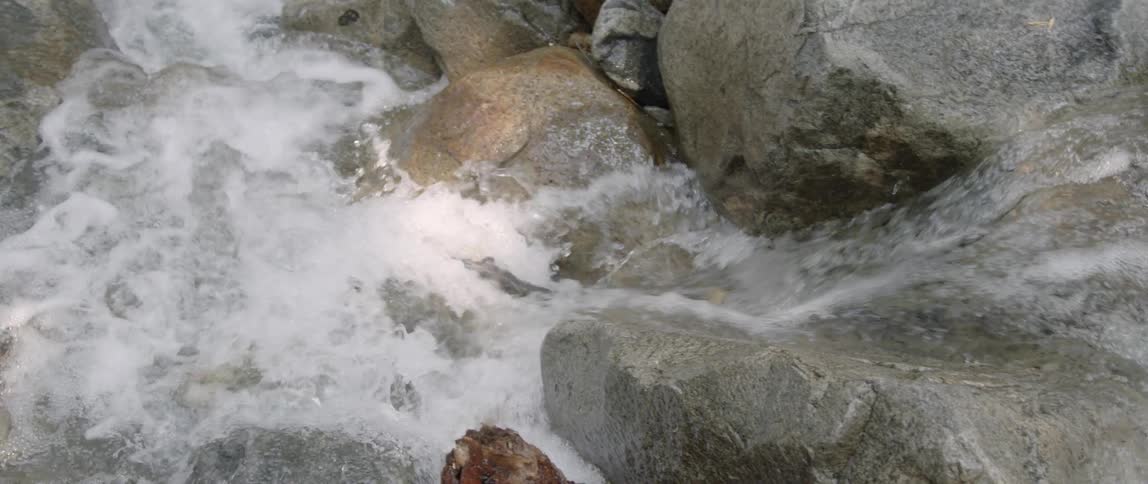 Water in a stream is cascading over boulders during the day