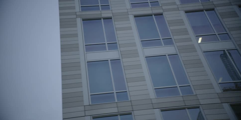 The building has many windows with lights on inside on a cloudy day