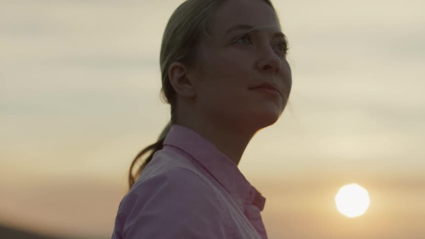 Woman holding a tablet outdoors at sunset
