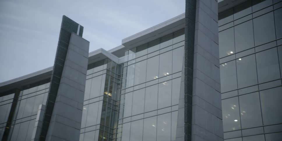Lights are on inside an all glass building in the city