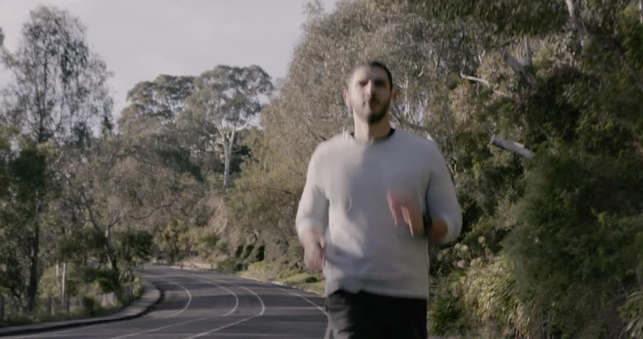 A man is running down the street as another rides their bicycle
