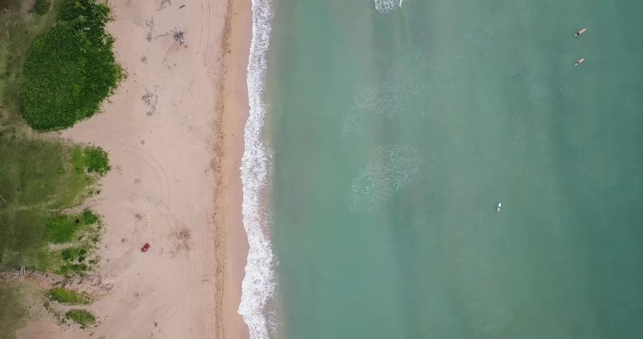 The waves are crashing against the shore as a person walks on the sand