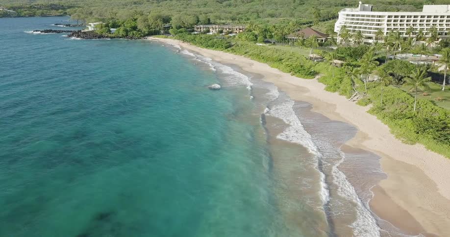 Waves lap the beach at a tropical resort on a sunny day