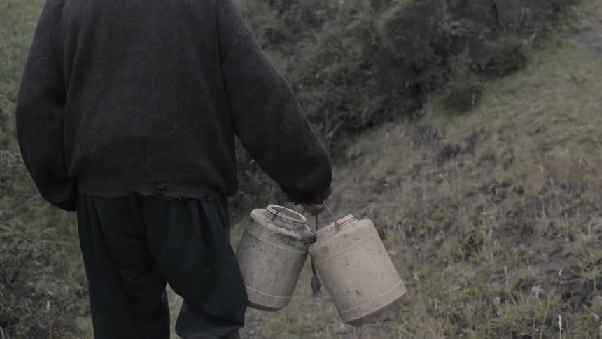 A man carries two canisters outside